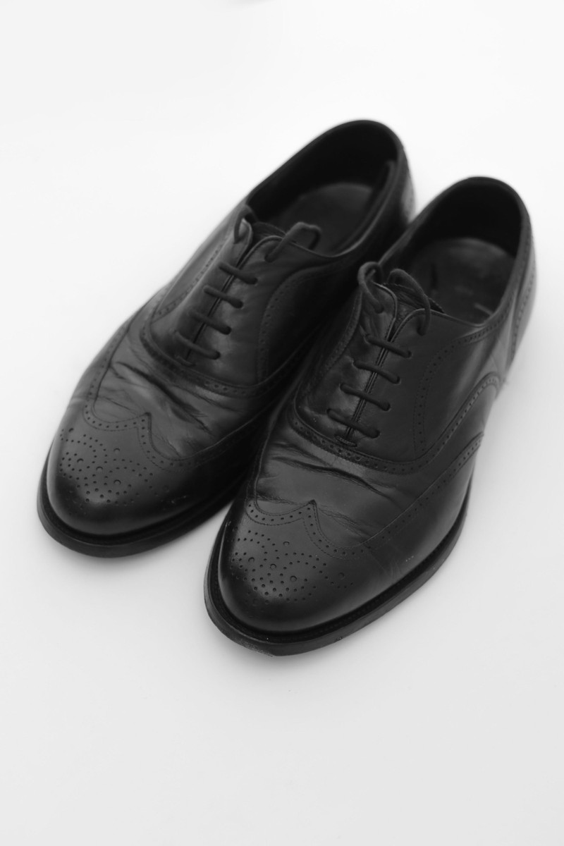 Black calf wingtip brogues on white.