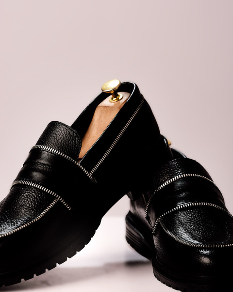 Black pebbled loafers with zip trims.