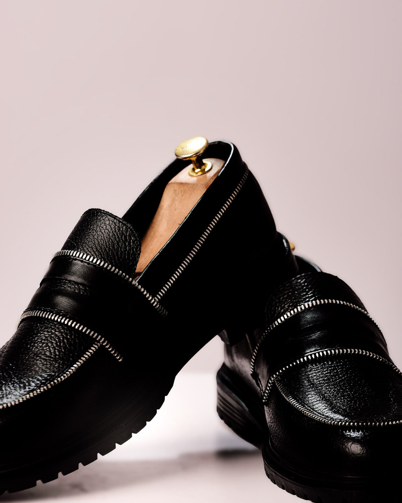 Black pebbled loafers with zip trims.