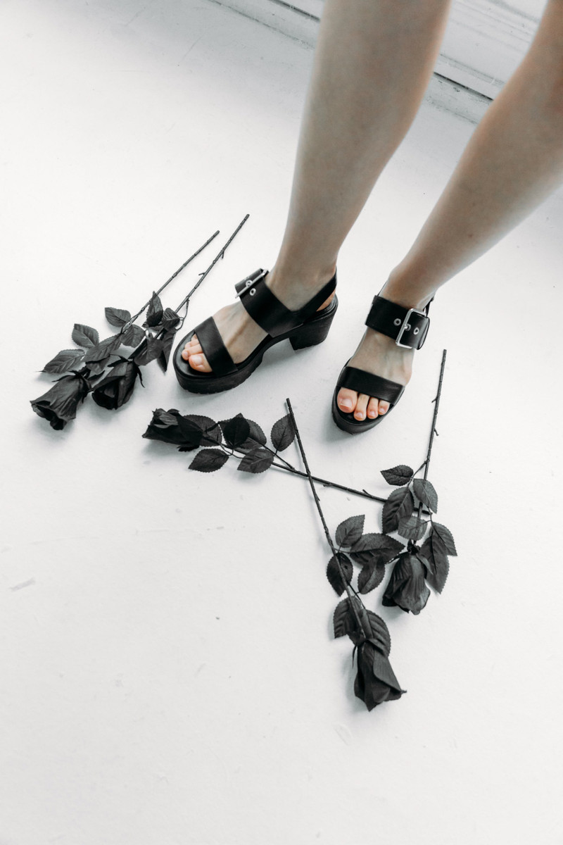Black buckle platform sandals, worn, with black roses.