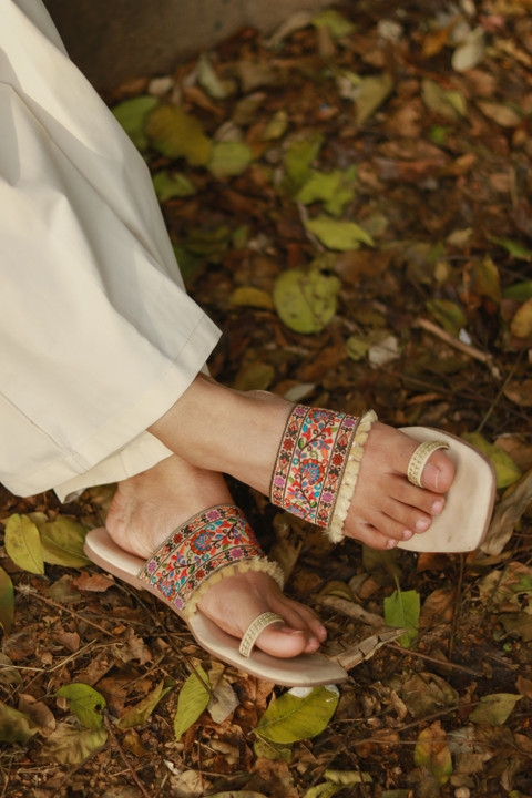 Embroidered toe-ring flats, worn, on fallen leaves.
