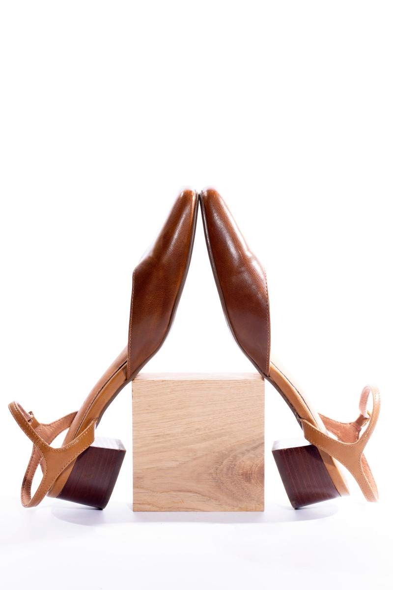 The tan strappy heels on a wooden block.