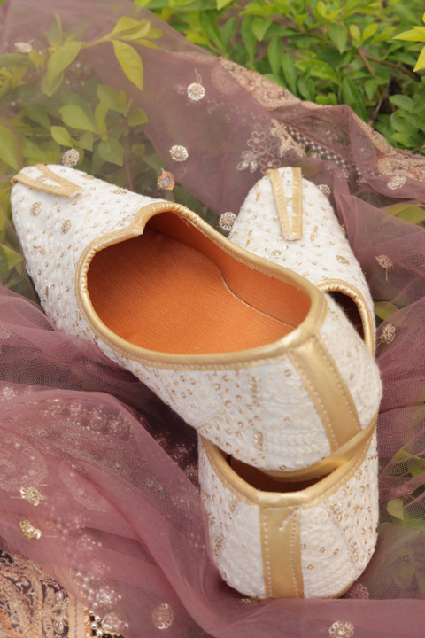 Ivory and gold embroidered juttis on a sheer dupatta.