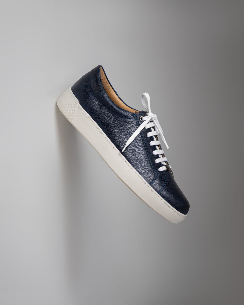 A navy leather sneaker with white laces.