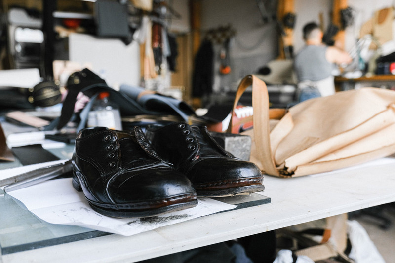 Handmade leather shoes on a cobbler's workbench.